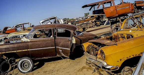 Stacked rusty and damaged junk cars in a junkyard, representing junk car selling services in Plano, TX.