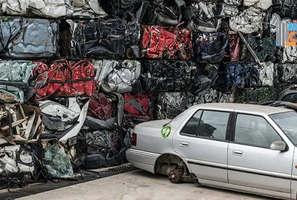 Stacked crushed cars and silver car at eco-friendly scrap yard disposal service in Irving, TX