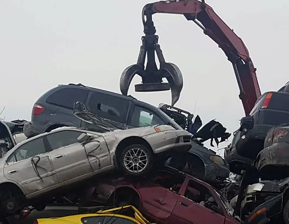 Mechanical claw lifting crushed cars for eco-friendly scrap yard car disposal in Carleton, TX