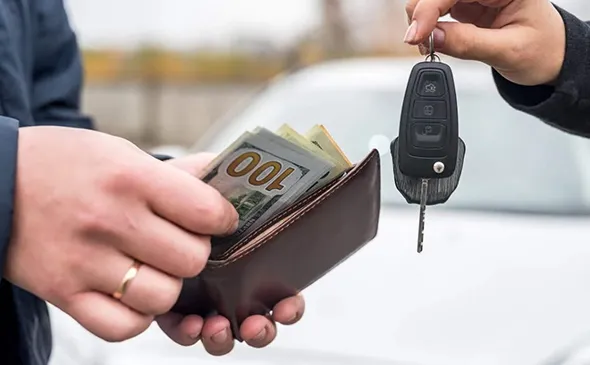 Hand holding cash and car keys for junk car removal in Midlothian, TX