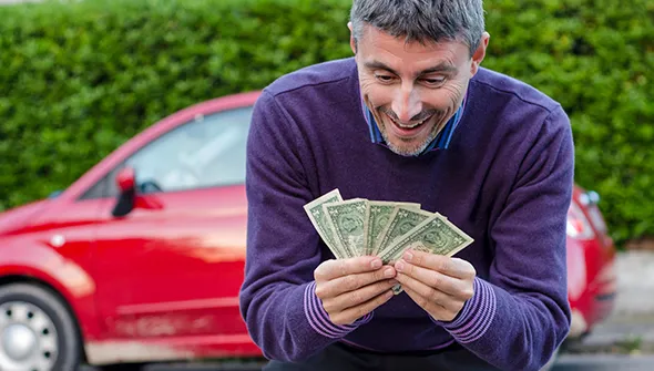 Man smiling and holding cash for instant junk car payment in Midlothian TX