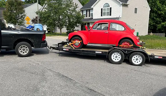 Red Volkswagen Beetle on flatbed trailer for same day junk car pickup in Arlington, TX